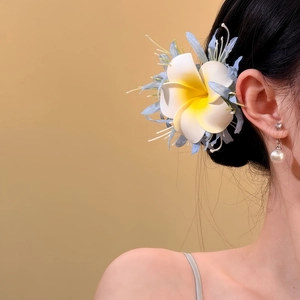 Nahaufnahme einer süßen Frangipani Stoffblumen-Haarklammer auf dem dunklen Haar eines Models