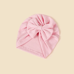 Detailed view of pink knitted baby turban hat featuring a large waffle texture bow