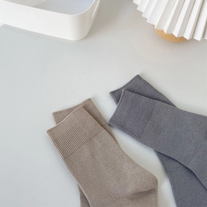 Minimalist Morandi style crew socks in dark grey and oatmeal colors on a white shelf