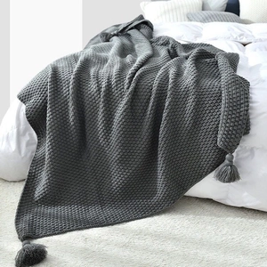 Macro detail of dark grey waffle knit throw blanket with decorative corner tassels