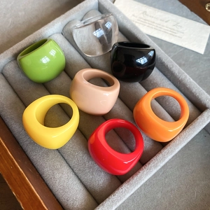 Close-up of colorful geometric oval resin rings neatly organized in a grey velvet jewelry box