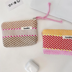 Detail of striped woven makeup bags with zipper and label on a clean desk workspace