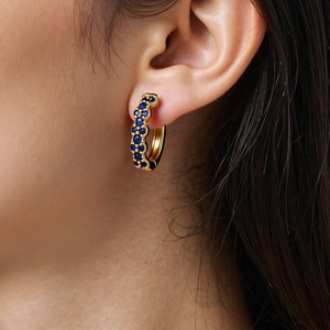 Close-up of vintage gold hoop earring with micro-paved blue zircons on a female model