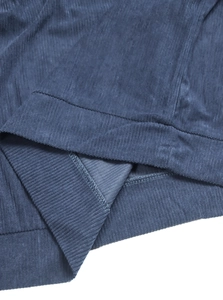 Detailed macro view of the blue corduroy fabric texture and precise stitching on the garment