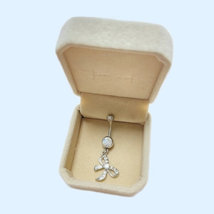 Piercing nombril nœud argenté avec strass blancs dans une boîte à bijoux en velours