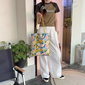 Détail du sac fourre-tout en toile à fleurs avec anse jaune et étiquette Sonikka