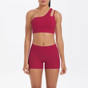 Detail of dark red one-shoulder sports bra and high-waisted fitness shorts on model