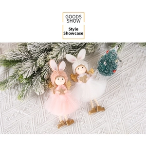 Detail of plush Christmas angel dolls with gold wings and tulle skirts on snowy pine background