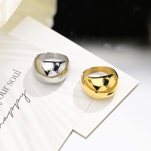 Anelli a cupola lucidi in oro e argento su carta bianca con ombre artistiche soft