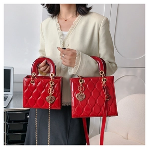 Detail of red quilted patent leather lady bags with metal heart charms and chain straps