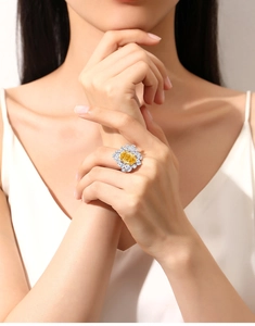 Macro shot of an oval yellow diamond flower ring worn by a model in silver metal