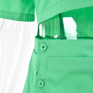 Detail der grünen Bluse mit seitlichem Ausschnitt und dekorativen Knopfverschlüssen