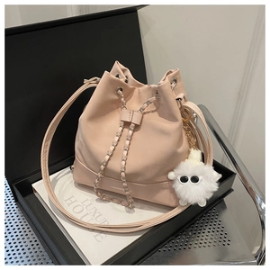 Detail of pink PU leather bucket bag with drawstring closure and plush pendant charm