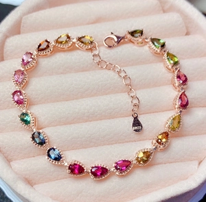 Detail of rose gold S925 bracelet with colorful teardrop gemstones in a pink jewelry box