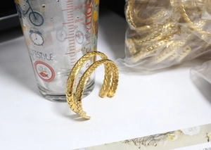 Detailed macro view of gold-plated wheat grain textured bangles in a stack