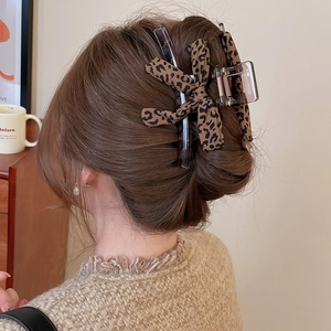 Detail of leopard print fabric bow hair claw clip styled in long hair with natural light