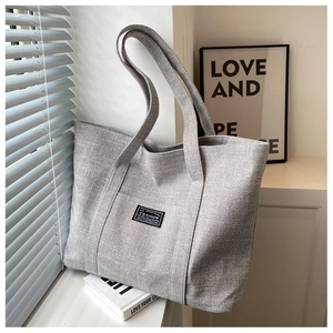 Close-up of gray large capacity tote bag featuring coarse canvas texture and fashion label