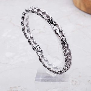 Dettaglio macro del bracciale a catena in acciaio inox con incisioni floreali nere