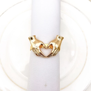 Detailed view of heart-shaped gold metal napkin ring on white dinner plate and cloth