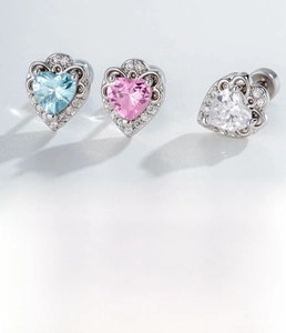 Detail of silver cartilage studs set with light blue, pink and white heart zircons