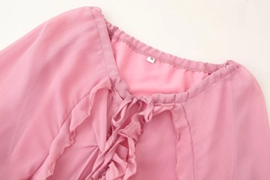 Détail de l'encolure en V en mousseline rose avec volants et étiquette de taille S