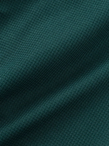Vue macro détaillée d'un tissu gaufré vert foncé avec des fibres textiles nettes