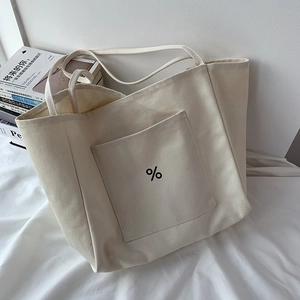 Macro detail of thick beige canvas tote bag with front pocket and contrast logo