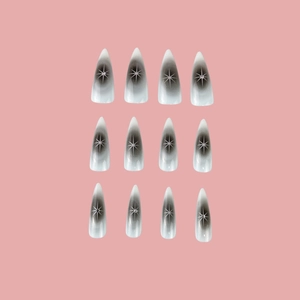 Y2K style long stiletto nails with black ombre design and white star patterns