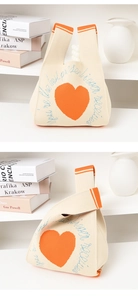 Close-up of beige knitted handbag featuring orange hearts and detailed textile texture