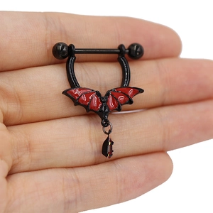 Macro shot of gothic bat nipple ring featuring red zircon pendant and black finish