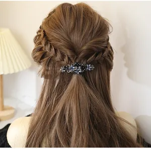 Detail of vintage elegant floral hair clip with blue rhinestones worn in braided hair