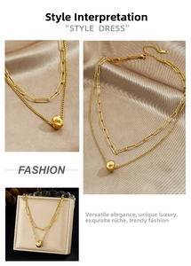 Detail view of gold layered chain necklace with geometric round bead pendant on satin fabric