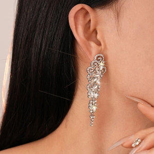 Close-up of sparkling leaf tassel earrings with rhinestones on a female model