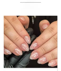 Makro-Detail von perlmuttfarbenen nude-rosa Mandelnägeln mit weißen Pünktchen-Mustern