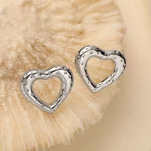 Pair of silver hollow heart stud earrings with dot texture on coral-like stone background