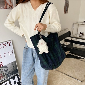 Detail of blue and green plaid tote bag with cute white sheep charm on black shoulder strap