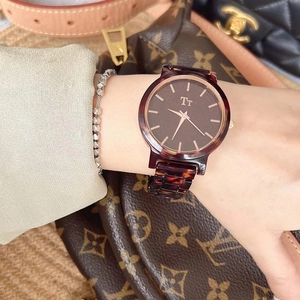 Detail of tortoise shell resin watch with dark brown dial and rose gold markers on wrist