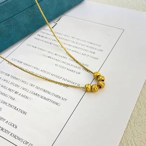 Detail of 18K gold plated beaded necklace with 5 matte textured frosted beads on box chain