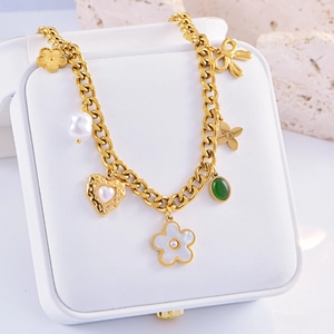 Detail of bohemian gold chain necklace with pearl heart and floral charms on display box