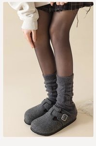 Détail de jambières en tricot torsadé gris foncé avec mules en feutre et collants noirs
