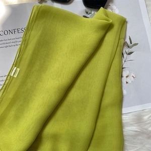Close-up of grass green lightweight polyester scarf fabric with material label
