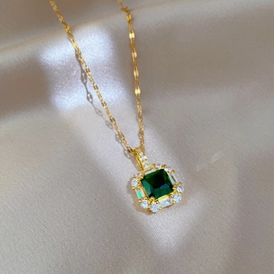 Macro shot of gold-plated necklace featuring a square green zircon pendant with pavé halo