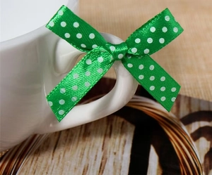 Detailed view of a green polka dot satin ribbon bow tied on a white cup handle