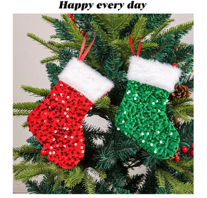 Close-up of red and green sequined Christmas stockings hanging on a tree with white faux fur