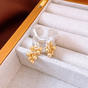 Detail of silver wavy band ring featuring hanging double golden bead charms in jewelry box