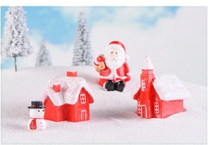 Detail view of snowy resin Christmas house figurines with Santa and snowman ornaments