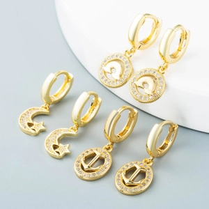 Detail of gold earrings set featuring moon star, anchor, and dolphin charms with crystals
