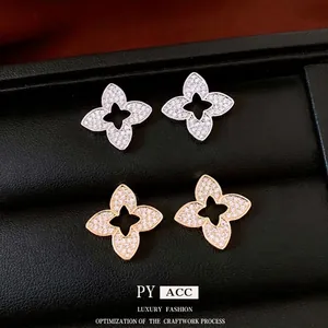 Luxurious flower stud earrings with gold plating and zircons on a black leather display