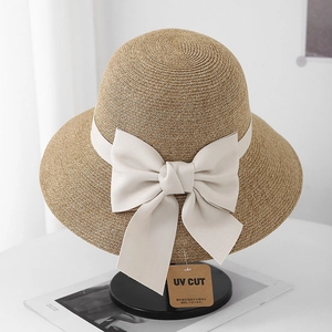 Close-up of woven straw sun hat with elegant beige ribbon bow and UV protection tag
