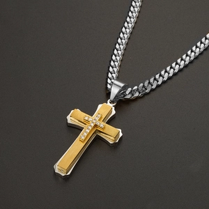 Detail of two-tone gold and silver cross pendant with crystals on a Cuban link chain